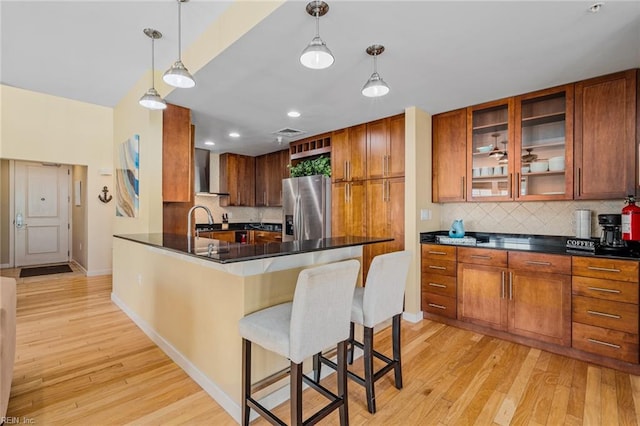 kitchen featuring light hardwood / wood-style floors, decorative backsplash, stainless steel refrigerator with ice dispenser, and decorative light fixtures