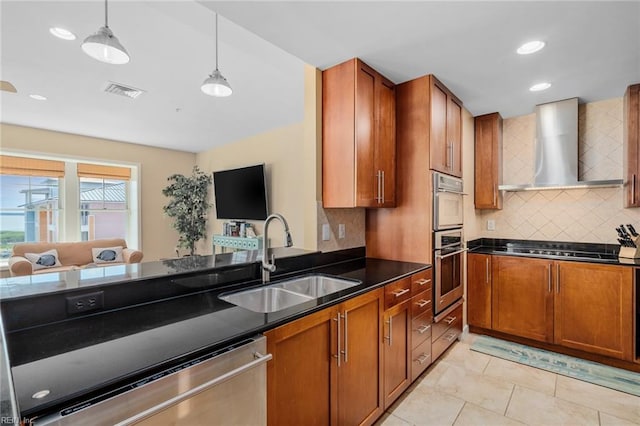 kitchen featuring decorative backsplash, appliances with stainless steel finishes, pendant lighting, wall chimney exhaust hood, and sink