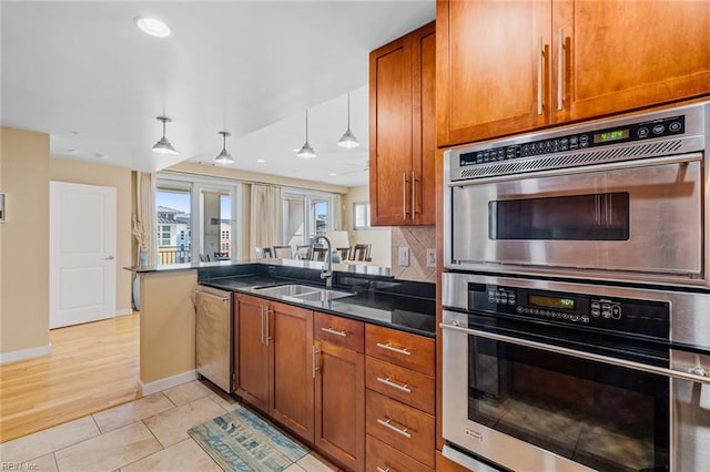 kitchen with decorative backsplash, light hardwood / wood-style flooring, stainless steel appliances, sink, and decorative light fixtures