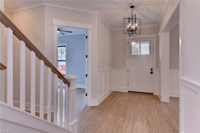 foyer entrance featuring crown molding, ceiling fan with notable chandelier, and light hardwood / wood-style floors