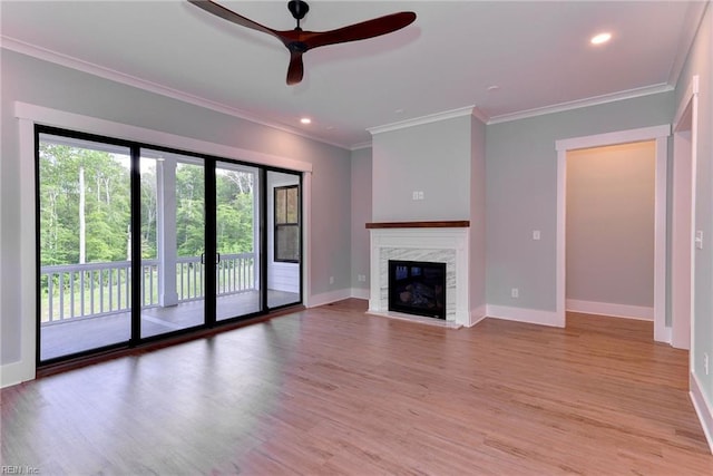 unfurnished living room with ceiling fan, crown molding, a premium fireplace, and light hardwood / wood-style flooring