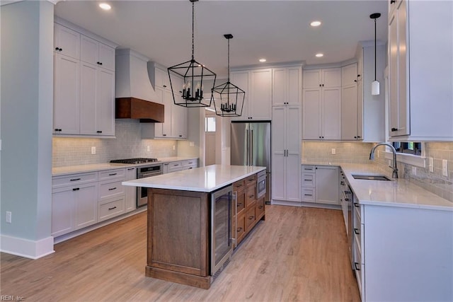 kitchen featuring sink, a center island, white cabinetry, light hardwood / wood-style floors, and beverage cooler