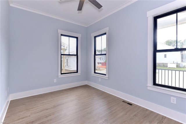 empty room with crown molding, a ceiling fan, baseboards, wood finished floors, and visible vents