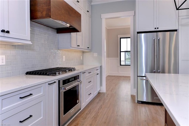 kitchen featuring ornamental molding, exhaust hood, white cabinets, and stainless steel appliances