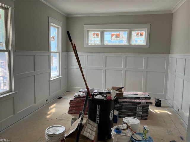 foyer entrance featuring crown molding, a wainscoted wall, and a decorative wall