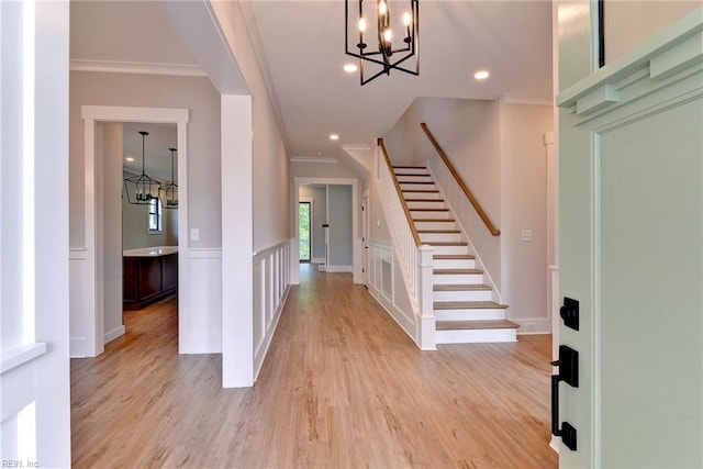 foyer featuring light hardwood / wood-style floors, crown molding, and a chandelier