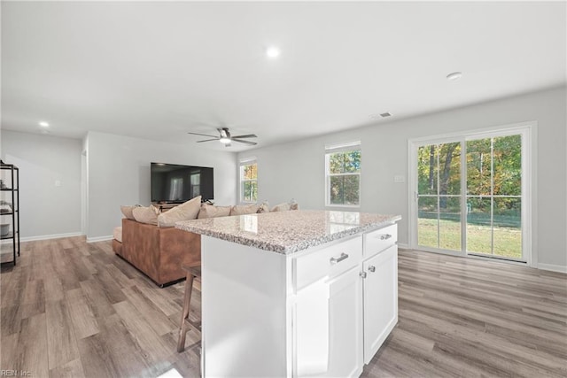 kitchen featuring light hardwood / wood-style flooring, white cabinetry, ceiling fan, and a kitchen island