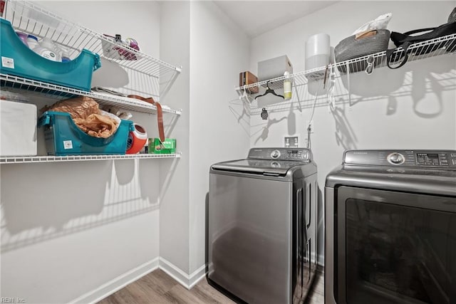 clothes washing area with hardwood / wood-style flooring and washer and clothes dryer