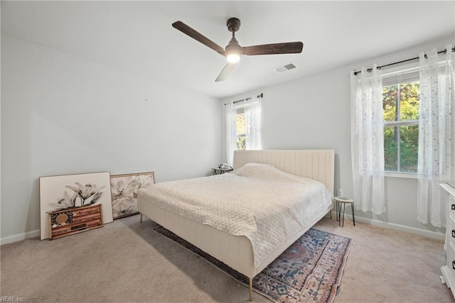 bedroom featuring multiple windows, light colored carpet, and ceiling fan