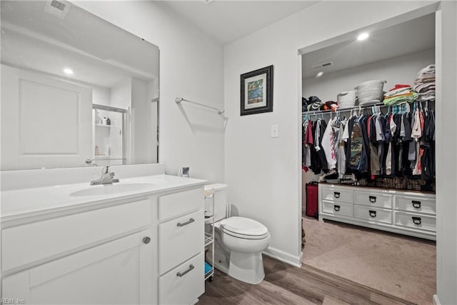 bathroom with vanity, hardwood / wood-style floors, toilet, and a shower with door