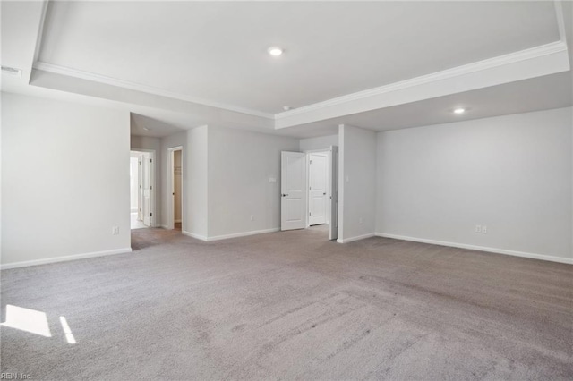 carpeted empty room featuring ornamental molding and a raised ceiling