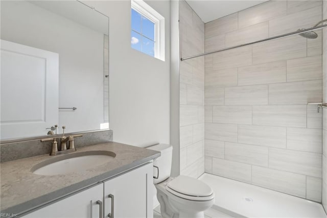 bathroom with vanity, toilet, and tiled shower