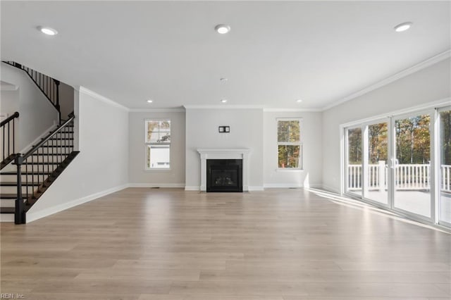 unfurnished living room featuring light hardwood / wood-style floors, ornamental molding, and plenty of natural light