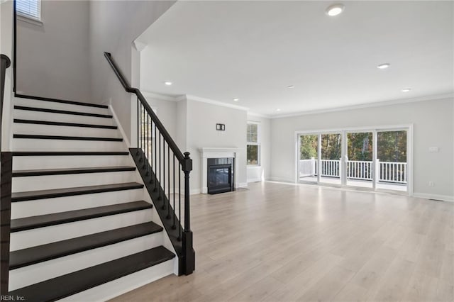 unfurnished living room with ornamental molding and light wood-type flooring