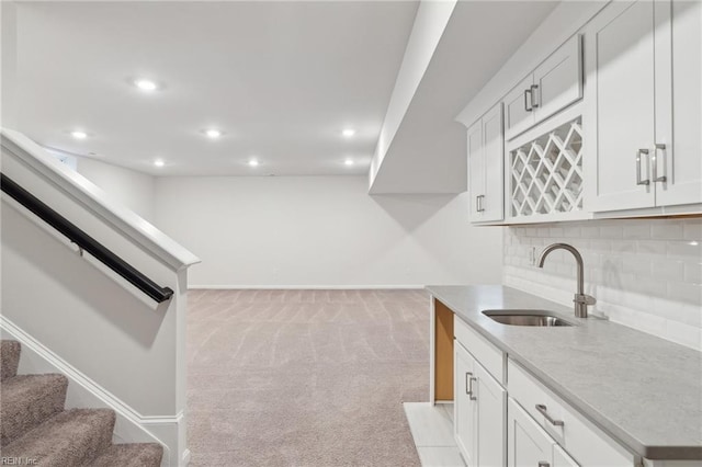 kitchen with white cabinetry, tasteful backsplash, sink, and light colored carpet