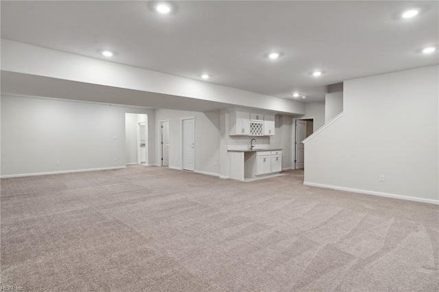 unfurnished living room with light carpet and sink