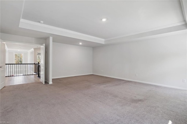 carpeted empty room with crown molding and a raised ceiling