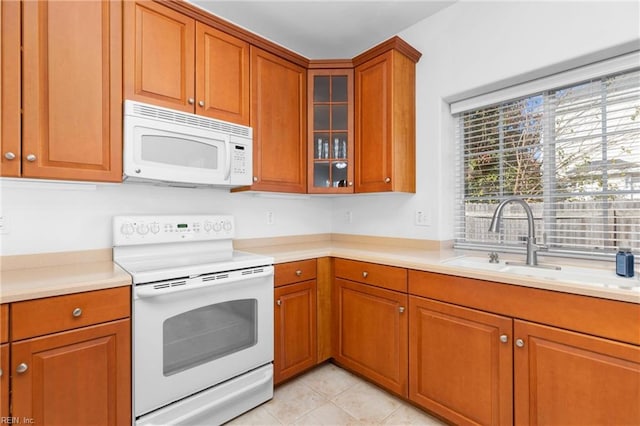 kitchen with sink, light tile patterned floors, and white appliances