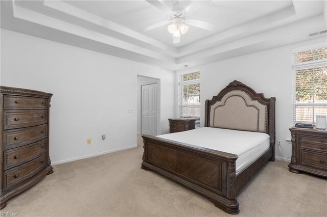 carpeted bedroom featuring multiple windows, a tray ceiling, and ceiling fan