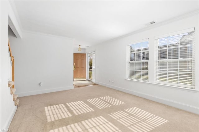 spare room featuring ornamental molding, light colored carpet, and a wealth of natural light