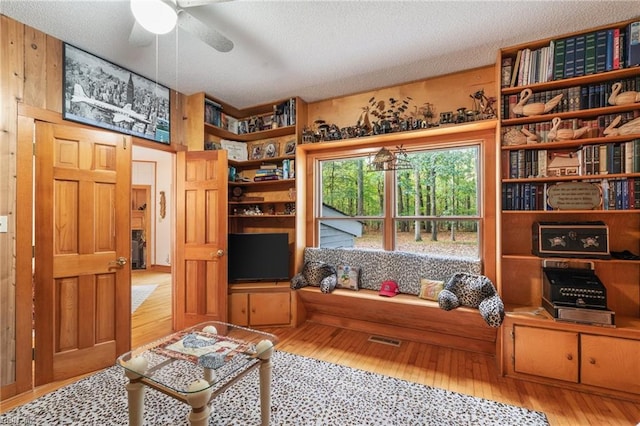 sitting room featuring light hardwood / wood-style flooring, a textured ceiling, and ceiling fan