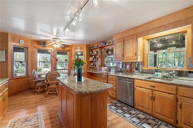 kitchen featuring light stone counters, light wood-type flooring, dishwasher, ceiling fan, and a center island