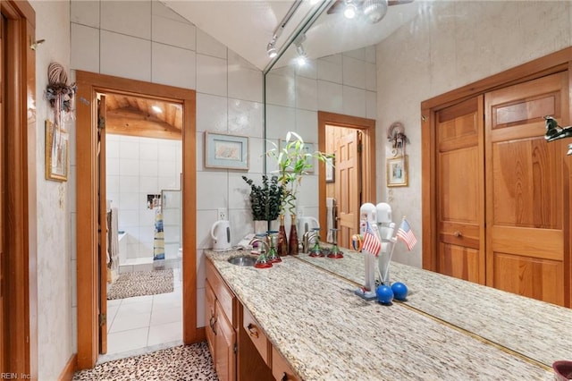 bathroom featuring vaulted ceiling, tile walls, tile patterned flooring, track lighting, and vanity