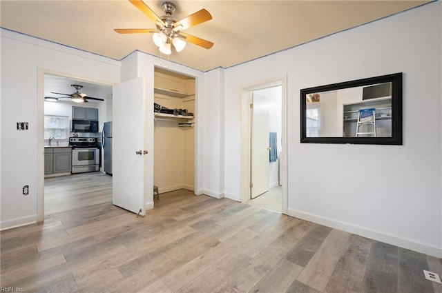 unfurnished bedroom with stainless steel fridge, ceiling fan, light hardwood / wood-style floors, ensuite bath, and sink