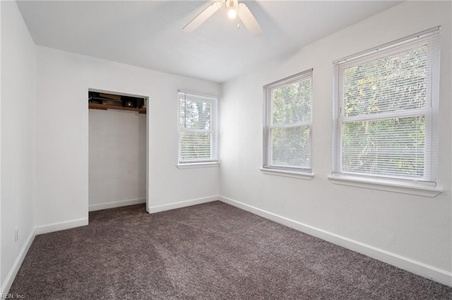 unfurnished bedroom with dark colored carpet, a closet, and ceiling fan