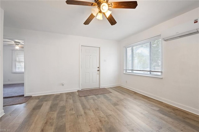 unfurnished room with an AC wall unit, light hardwood / wood-style flooring, a healthy amount of sunlight, and ceiling fan