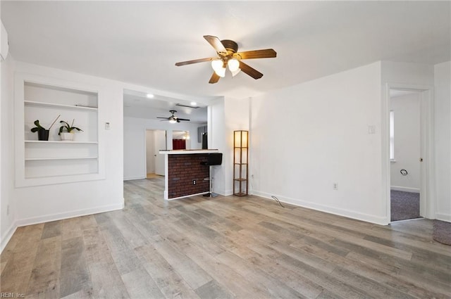 unfurnished living room with hardwood / wood-style floors, built in features, and ceiling fan