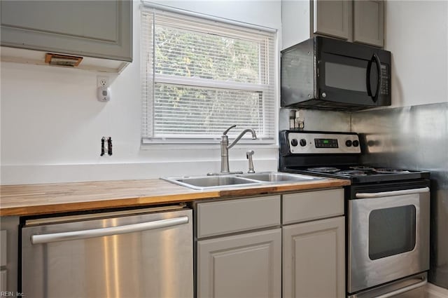 kitchen with decorative backsplash, wood counters, sink, gray cabinetry, and stainless steel appliances