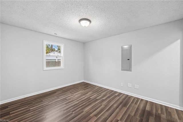 spare room with dark wood-type flooring, electric panel, and a textured ceiling