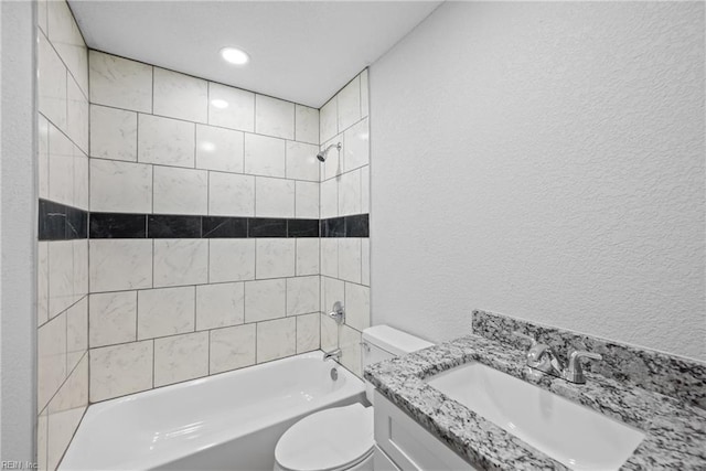 full bathroom featuring tiled shower / bath, vanity, and toilet