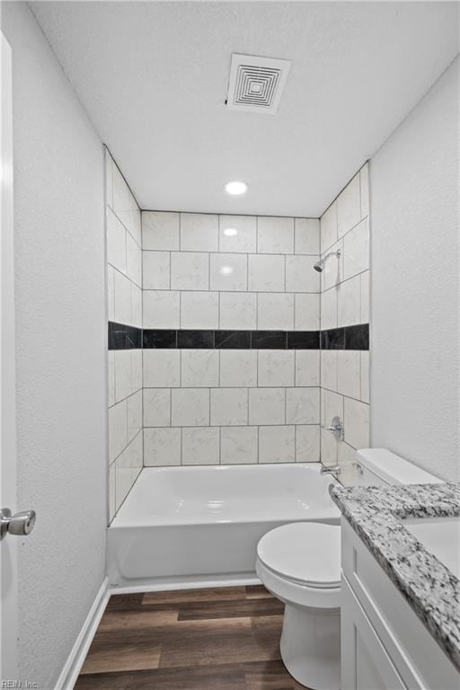 full bathroom with vanity, tiled shower / bath combo, hardwood / wood-style flooring, and toilet