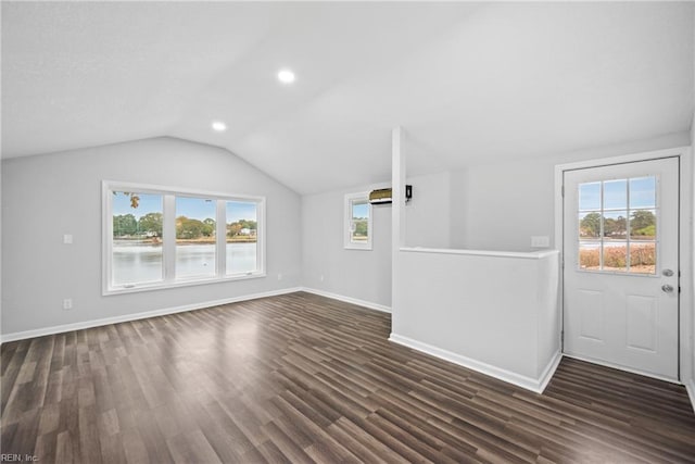 unfurnished living room featuring a wealth of natural light, vaulted ceiling, and dark hardwood / wood-style flooring