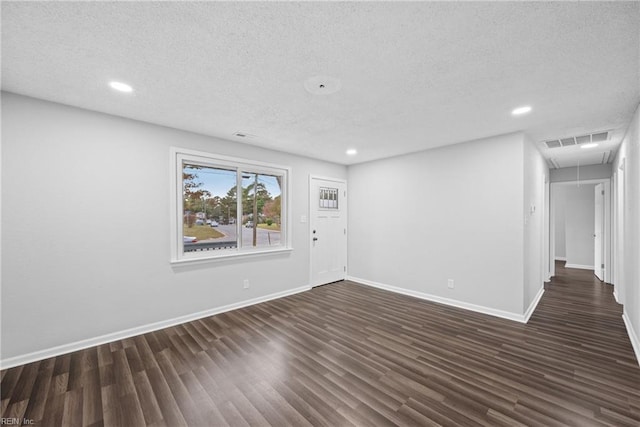 empty room with dark hardwood / wood-style floors and a textured ceiling