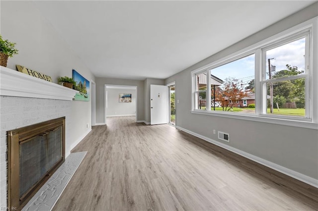 unfurnished living room with a brick fireplace and hardwood / wood-style flooring