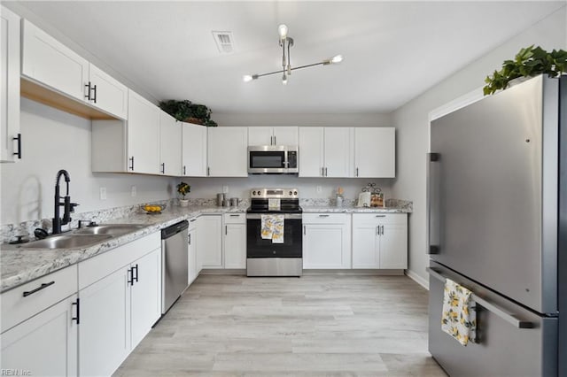 kitchen featuring light stone counters, white cabinetry, appliances with stainless steel finishes, sink, and light hardwood / wood-style floors