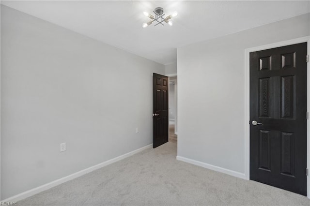 unfurnished room with light carpet and a notable chandelier