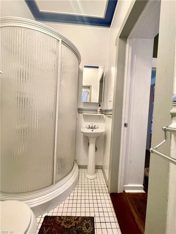 bathroom featuring tile patterned flooring, toilet, and a shower with door