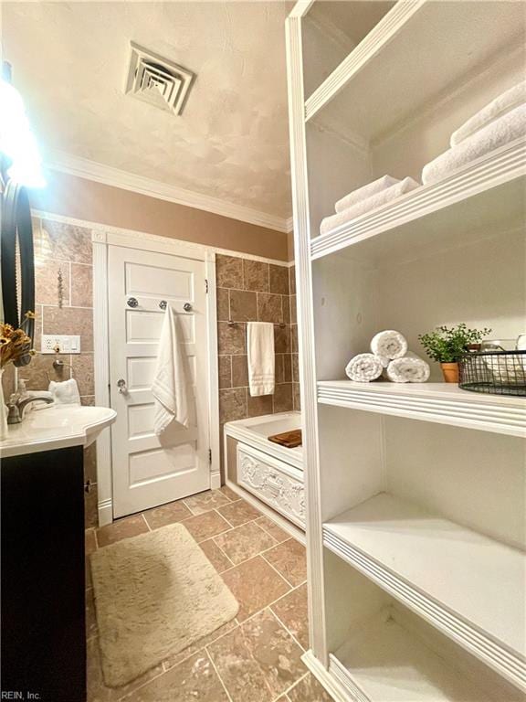 bathroom with shower / bath combination, vanity, ornamental molding, and tile walls