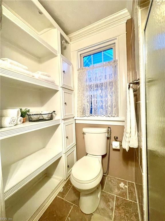 bathroom featuring ornamental molding, an enclosed shower, and toilet