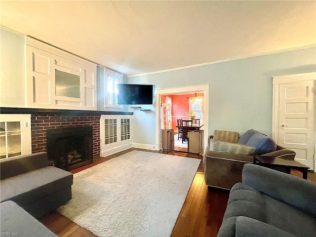 living room with a fireplace, a healthy amount of sunlight, ornamental molding, and dark wood-type flooring