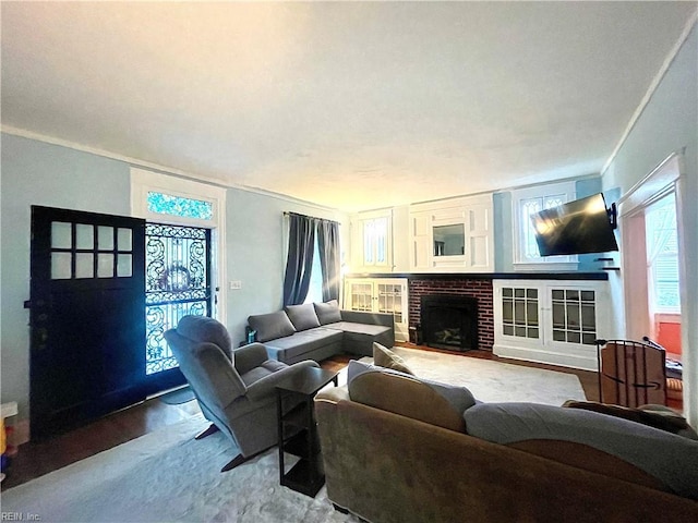 living room with crown molding, light hardwood / wood-style flooring, and a brick fireplace