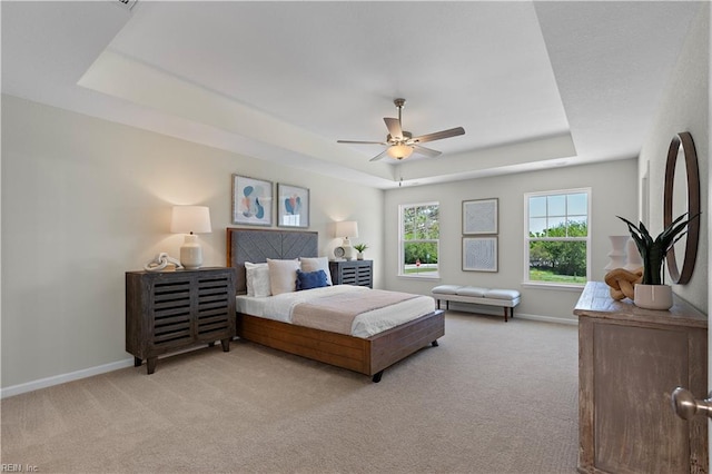 carpeted bedroom featuring a raised ceiling and ceiling fan