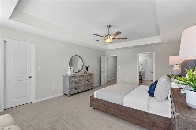 bedroom with ceiling fan, light carpet, and a tray ceiling