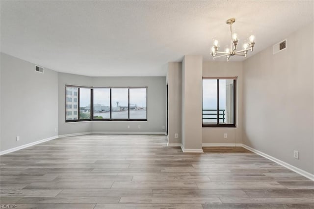 spare room with wood-type flooring and an inviting chandelier