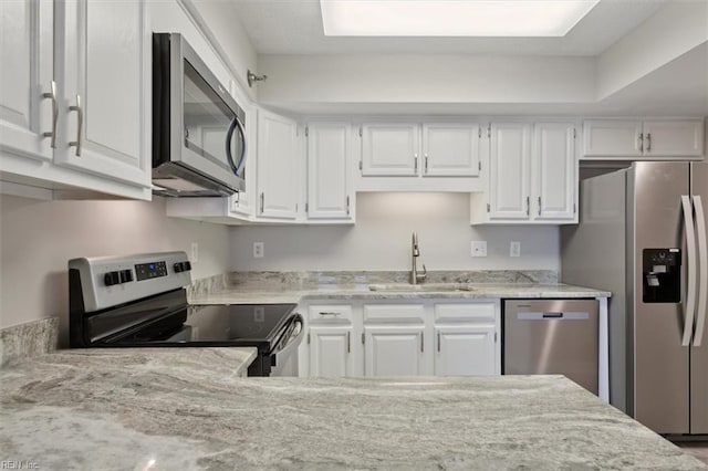 kitchen with white cabinetry, light stone countertops, stainless steel appliances, and sink