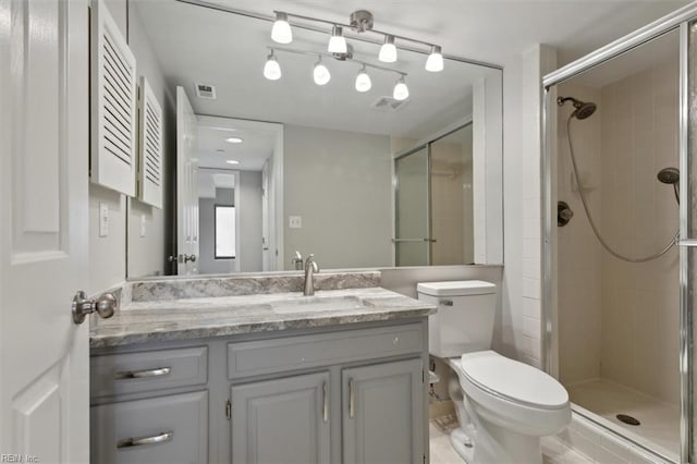 bathroom with toilet, vanity, and a shower with door